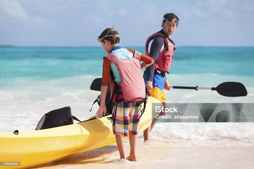 Father and son pulling kayak Father and son kayaking at tropical ocean Canoeing Stock Photo