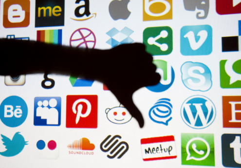 London, United Kingdom - February 17, 2014: Silhouetted thumbs down in front of social media and technology logos. Logos include instagram, google plus, Skype,