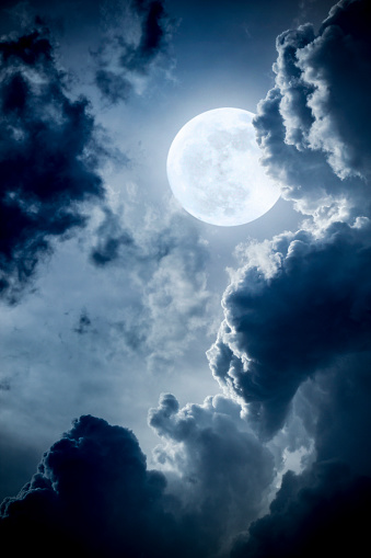 This dramatic photo illustration of a nighttime scene with brightly lit clouds and large, full, Blue Moon would make a great background for many uses.