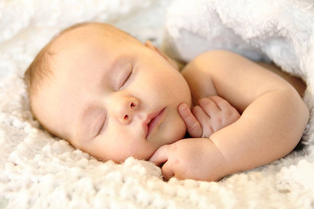 istock Newborn Infant Girl Sleeping Peacefully in White Blankets 475339154