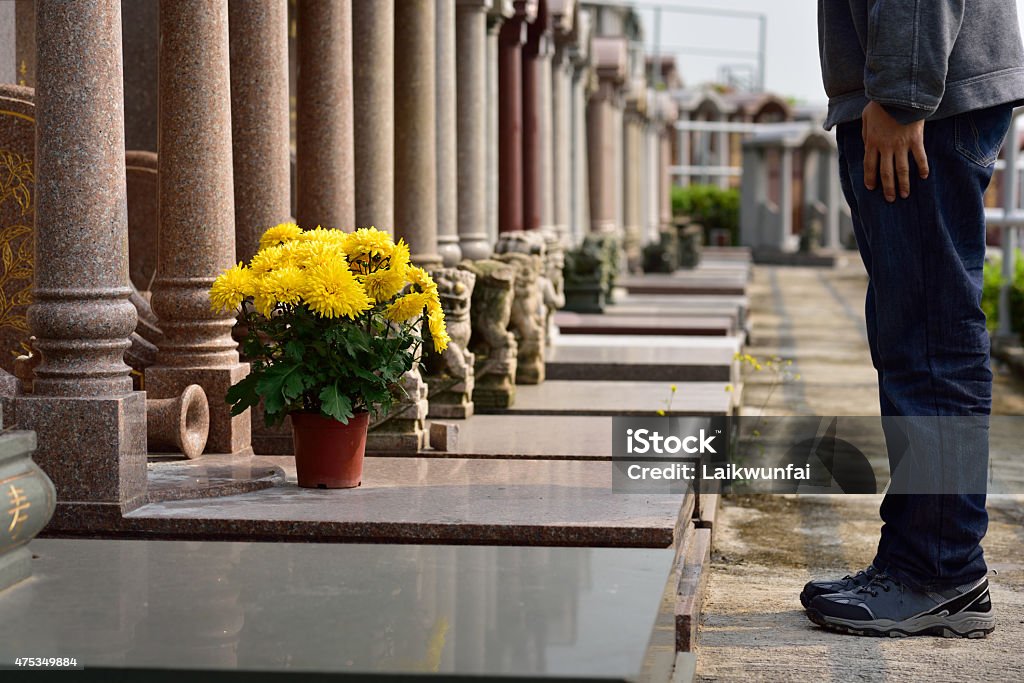 man put flower in front of tomb of ancestor Cemetery Stock Photo