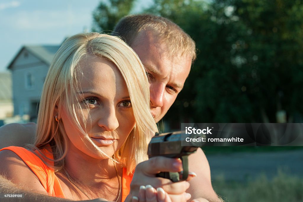 Man is teaching his girlfriend to shoot. Young man is teaching his girlfriend to shoot by pneumatic handgun. Learning Stock Photo