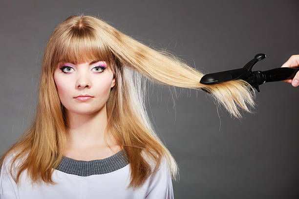 istock woman making hairstyle with hair iron 475359340