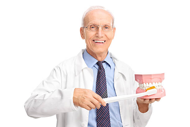 istock Mature dentist holding large toothbrush and a denture 475359528