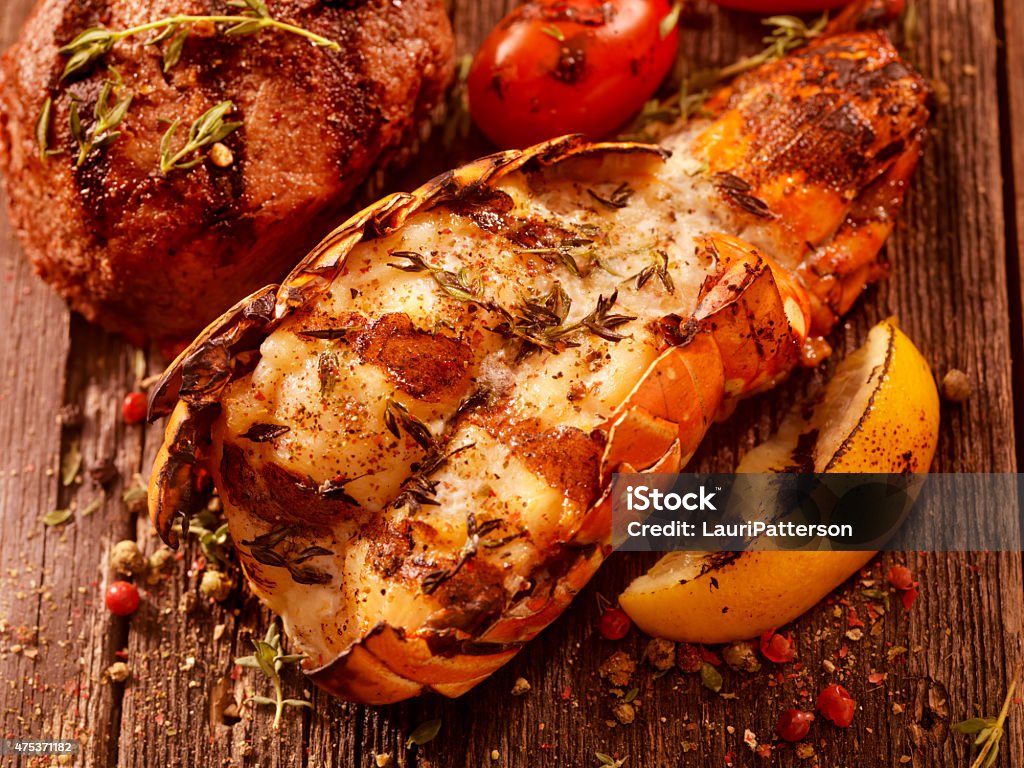 BBQ Grilled Lobster Tail and Steak Fillet BBQ Grilled Lobster Tail and Steak Fillet with Fresh Herbs, Grilled Lemon and Tomatoes -Photographed on Hasselblad H3D2-39mb Camera Lobster - Seafood Stock Photo