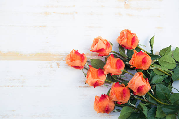 bunch of beautiful orange roses on a white vintage wooden background