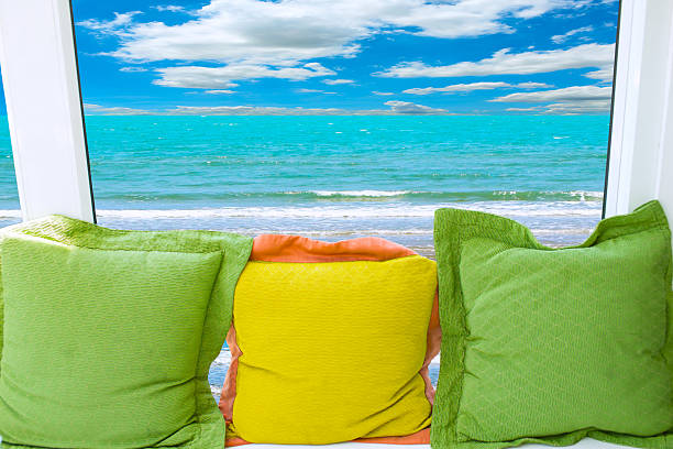 Colorful pillow.  Blurry ocean and sky in background.