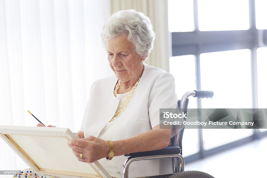 Staying busy in her senior years An elderly woman sitting in her wheelchair and painting in the retirement home 80-89 Years Stock Photo