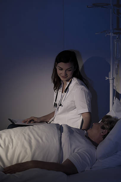 Doctor talking with ill patient Doctor talking with ill patient staying in hospice night hospital bed stock pictures, royalty-free photos & images