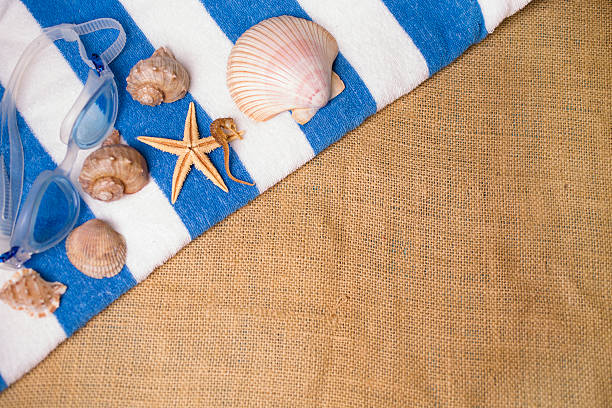 istock Summer vacation scene. Seashells, swim goggles on beach towel. 475382798