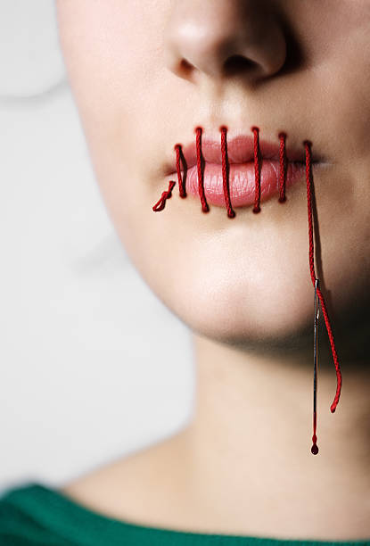 Mouth Sewn Shut Young woman with her mouth sewn shut. woman stitching stock pictures, royalty-free photos & images