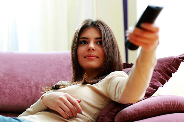 istock beautiful woman lying on the sofa with remote control 475385183