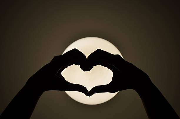 istock Heart shape woman hand making on the light  Silhouette 475385529