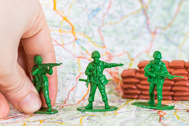 istock Human hand playing war with green plastic soldier with rifle 475388994