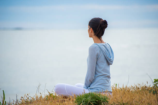 istock Woman meditating face to the ocean 475389052