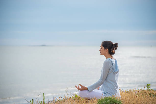 istock Woman meditating face to the ocean 475389054