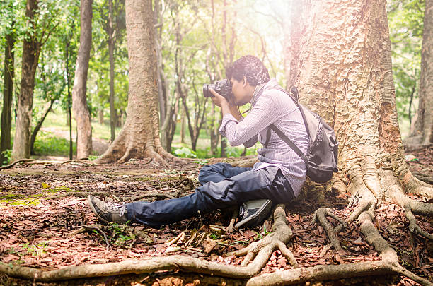 istock Photographer taking photos sitting under a big tree 475392288