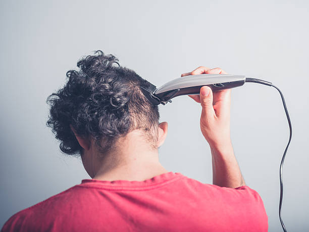 Young man cutting his hair at home