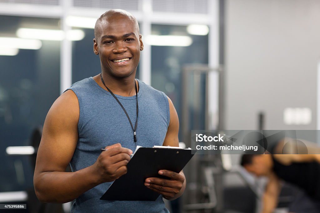 young african american male personal trainer young african american male personal trainer holding clipboard in gym Fitness Instructor Stock Photo