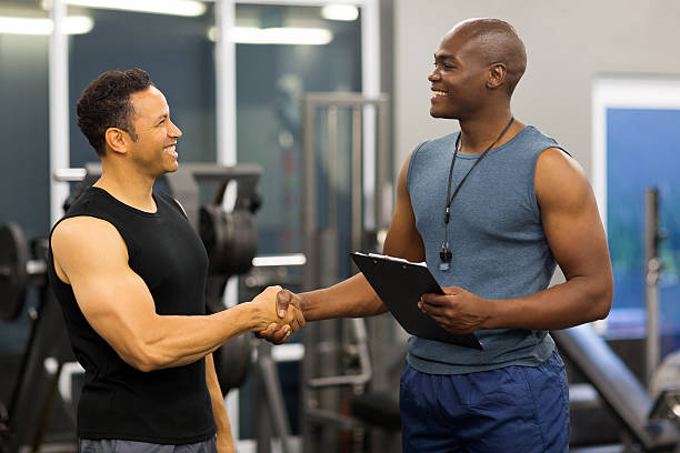 istock african gym trainer handshaking with mid age client 475396682
