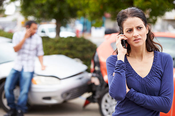 Female Driver Making Phone Call After Traffic Accident Female Driver Making Phone Call After Traffic Accident With Crash In Background. car accident stock pictures, royalty-free photos & images
