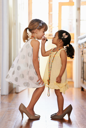 Two dressed up little girls wearing over-sized high heel shoes
