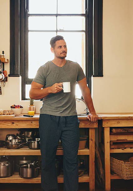 Relaxed young man having coffee at home in kitchen