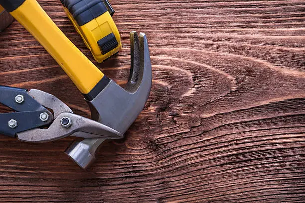 Claw hammer nippers and tape-measure on wood board construction concept 