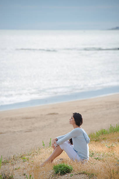 istock Woman meditating face to the ocean 475417032