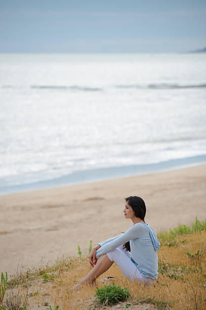 istock Woman meditating face to the ocean 475417058