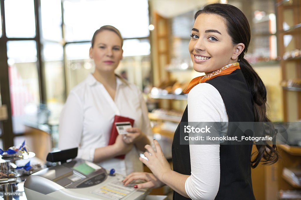 Client in shop paying at cash register Client at shop paying at cash register with saleswoman Saleswoman Stock Photo
