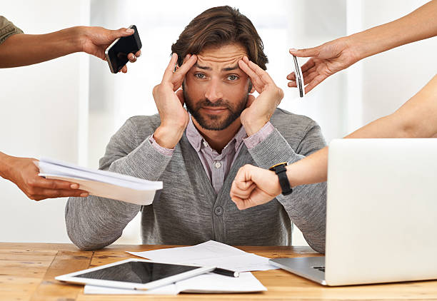 Nobody thought of bringing a headache pill to the party? A cropped shot of a handsome businessman under strain as colleagues request various things from him versatility stock pictures, royalty-free photos & images