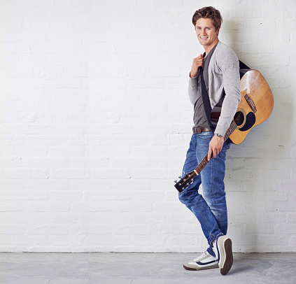 Portrait of a handsome young man standing with a guitar