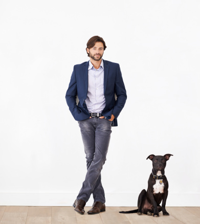A handsome man standing next to his dog - portrait