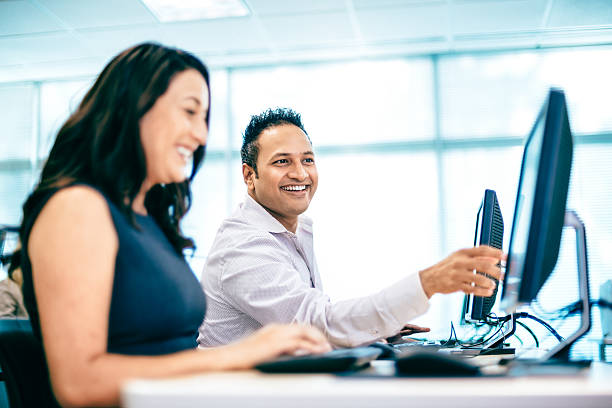 Computer Lab Hispanic woman and Indian man collaborating in Computer Lab. computer lab stock pictures, royalty-free photos & images