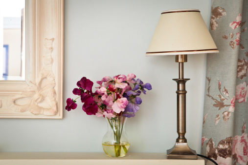 Lamp, flowers and a mirror in a vintage bedroom