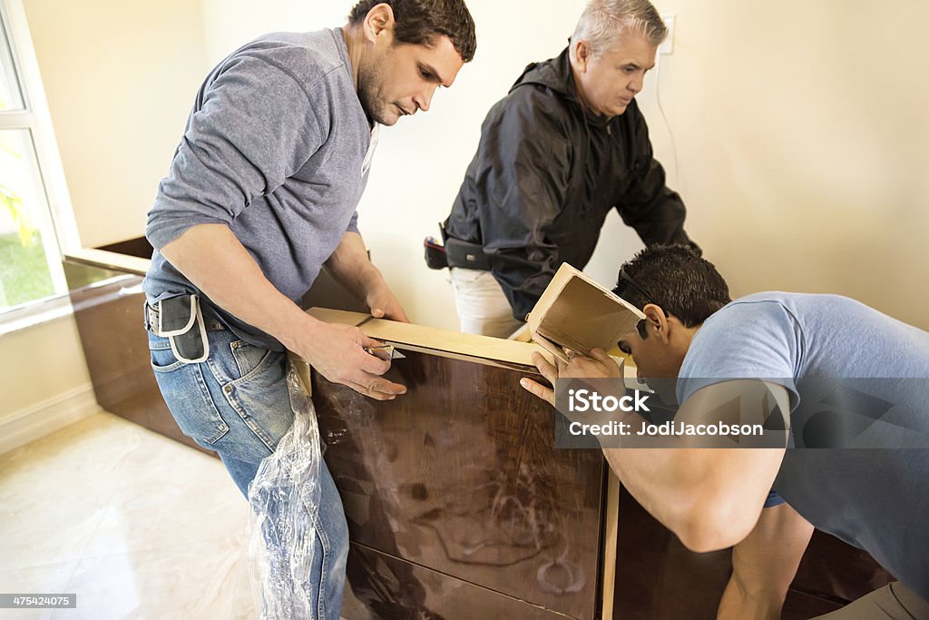 Assembling custom made home office furniture Workers are installing custom cabinetry in a home office.  RM Blue-collar Worker Stock Photo