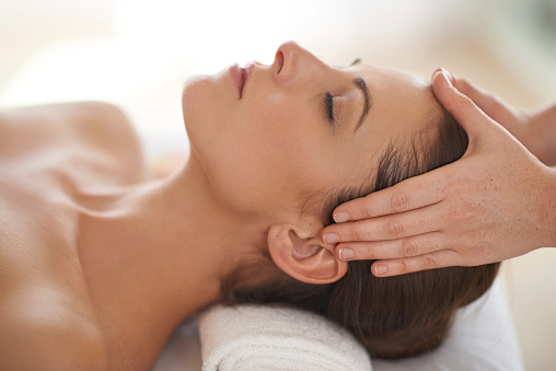 Close up shot of a young woman receiving a head massage at a spa