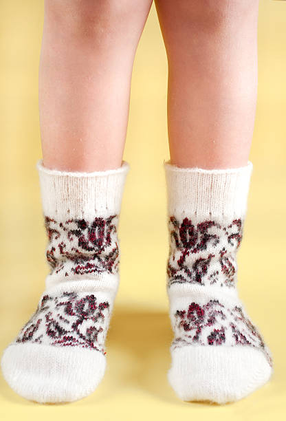istock Children's feet in wool socks on a yellow background 475427583