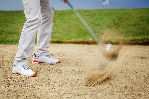 Professional male golf player hitting by iron from bunker