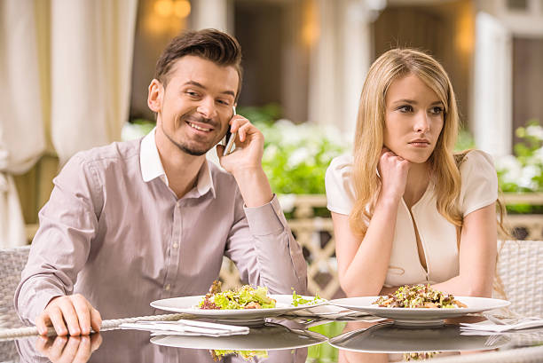 Romantic date Woman is getting bored in restaurant while her boyfriend is talking on the phone. couple on bad date stock pictures, royalty-free photos & images