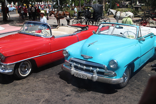 Havana, Сuba - April 7, 2015: Classic American cars parked in old town Havana in Cuba. Oldsmobile cars are often used as a tourist taxis in Cuba. Photo depicts taxi drivers waiting for tourists.