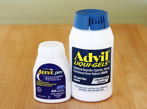 Advil and Aleve Pain Reliever Medicines West Palm Beach, USA - May 24, 2015: Two containers of pain killers. One holds Advil Liqui-Gels capsules. Advil is a pain reliever and fever reducer that contains ibuprofen, an NSAID. Advil is a Pfizer product. The second contains Aleve PM sleep aid and pain reliever caplets. Aleve is a Bayer product.  bayer schering pharma ag photos stock pictures, royalty-free photos & images