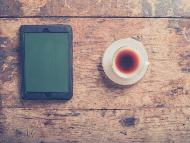 istock Tablet and coffee on wooden table 475428562