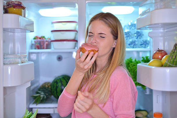 istock Woman eating a donut at night 475428574