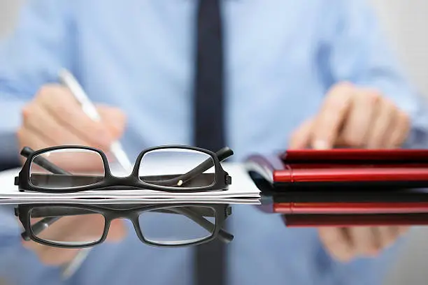 Photo of blurred businessman is working in office , focus is on eyeglasses