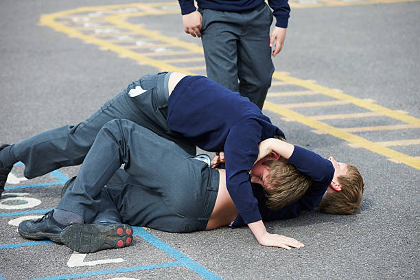 Two Boys Fighting In School Playground Two Boys Fighting In School Playground During Break Time schoolyard fight stock pictures, royalty-free photos & images