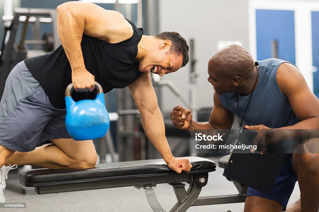 personal trainer training man with kettle bell personal trainer training man with heavy kettle bell Fitness Instructor Stock Photo