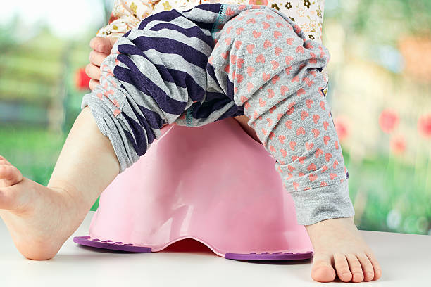 istock Children's legs hanging down from a chamber-pot on a green 475432342