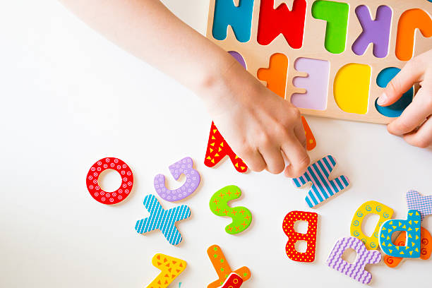 istock Education, child's hands sorting colorful letters in alphabet puzzle 475433100